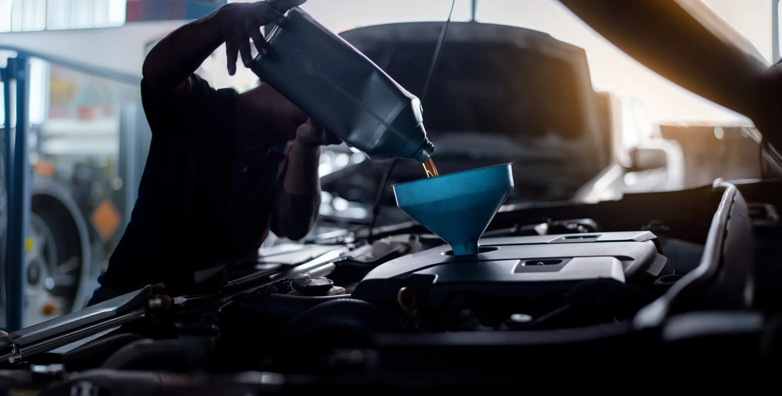 Mecânico colocando óleo no motor de um carro